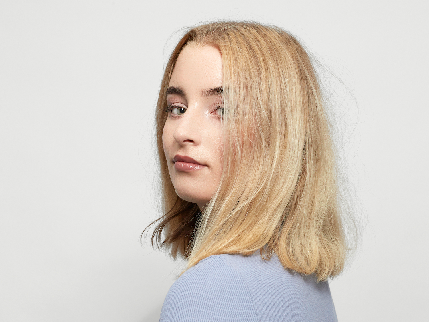 Model mit blonden Haare und einem Bob vor einem weißen Hintergrund