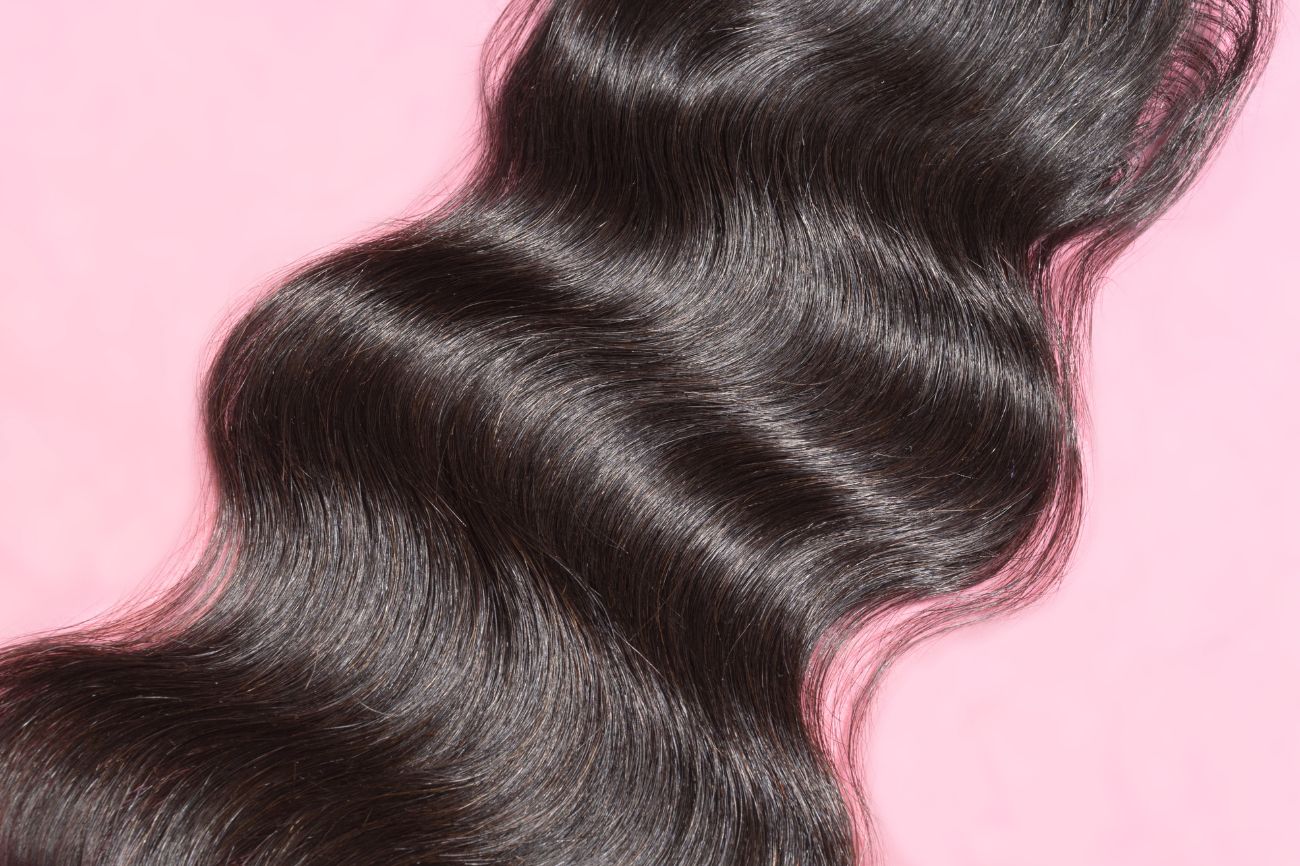 Nahaufnahme von dunklen Haaren auf pinken Hintergrund