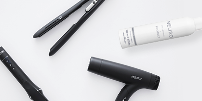 Neuro Tools, darunter Glätteisen, Lockenstab und Föhn in Schwarz, sowie eine Sprühflasche, auf hellem Hintergrund.