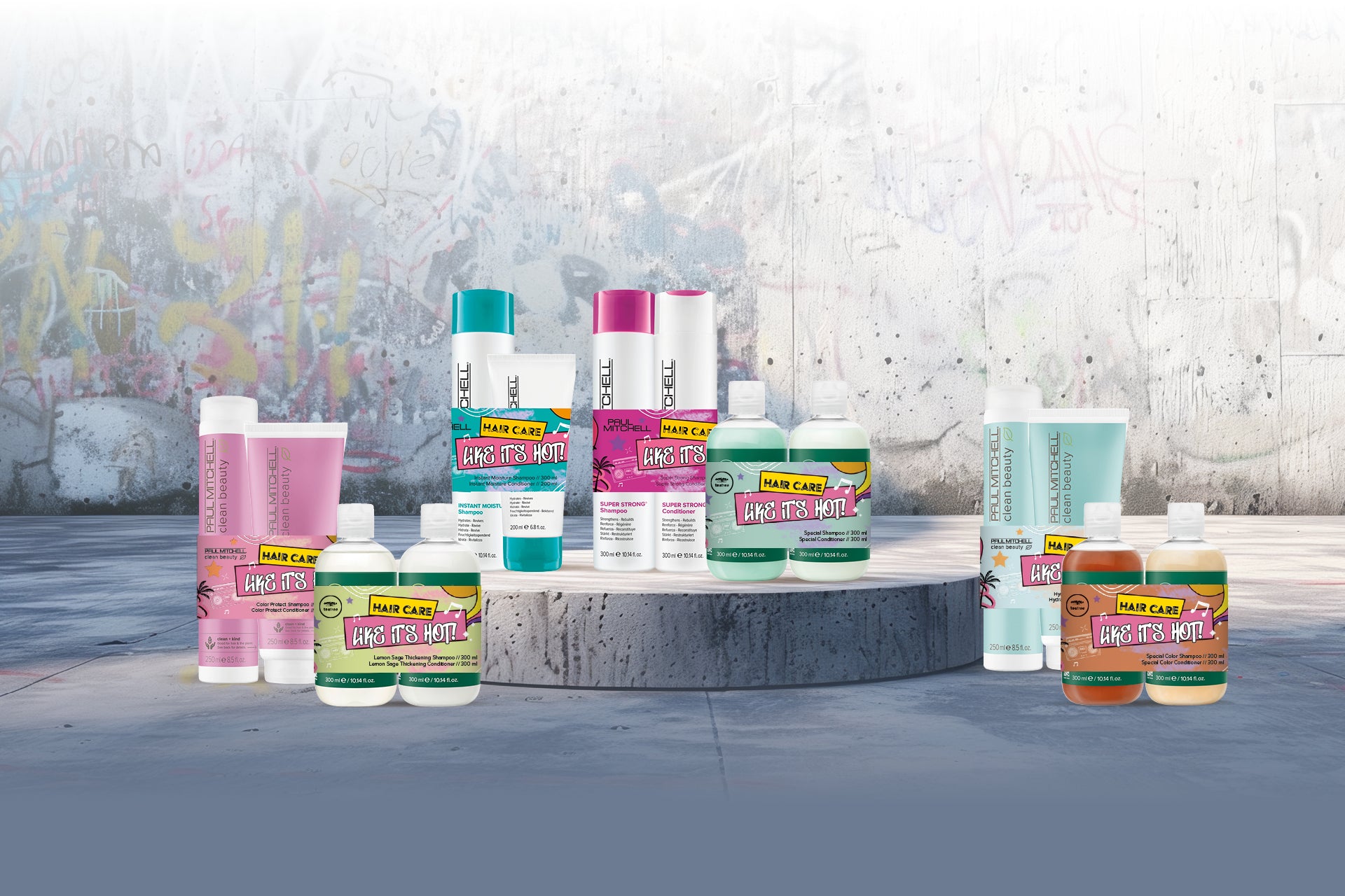 Sieben Paul Mitchell-Produktsets arrangiert vor einem grauen Hintergrund mit etwas Graffiti. 