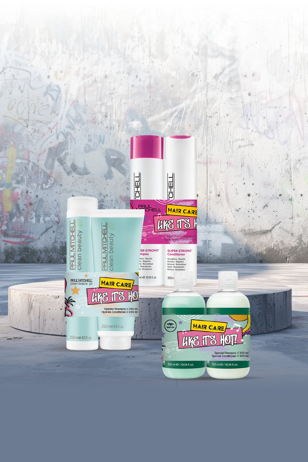 Drei Paul Mitchell-Produktsets arrangiert vor einem grauen Hintergrund mit etwas Graffiti. 
