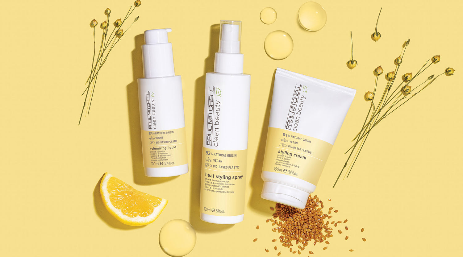 Stylingprodukte auf gelbem Hintergrund mit Leinsamen, Blumen und Citrus – für Hitzeschutz & Halt.