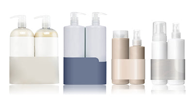 Vier Produktsets in Pump- und Sprühflaschen, jeweils mit farbiger Banderole in Creme, Blau, Beige und Silber.