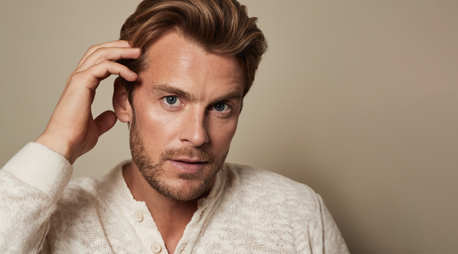 Mann mit vollem, gesund aussehendem Haar berührt seine Kopfhaut – ideal inszeniert für Paul Mitchell Tea Tree Scalp Care, eine Pflegeserie für Kopfhaut und Haarwachstum.